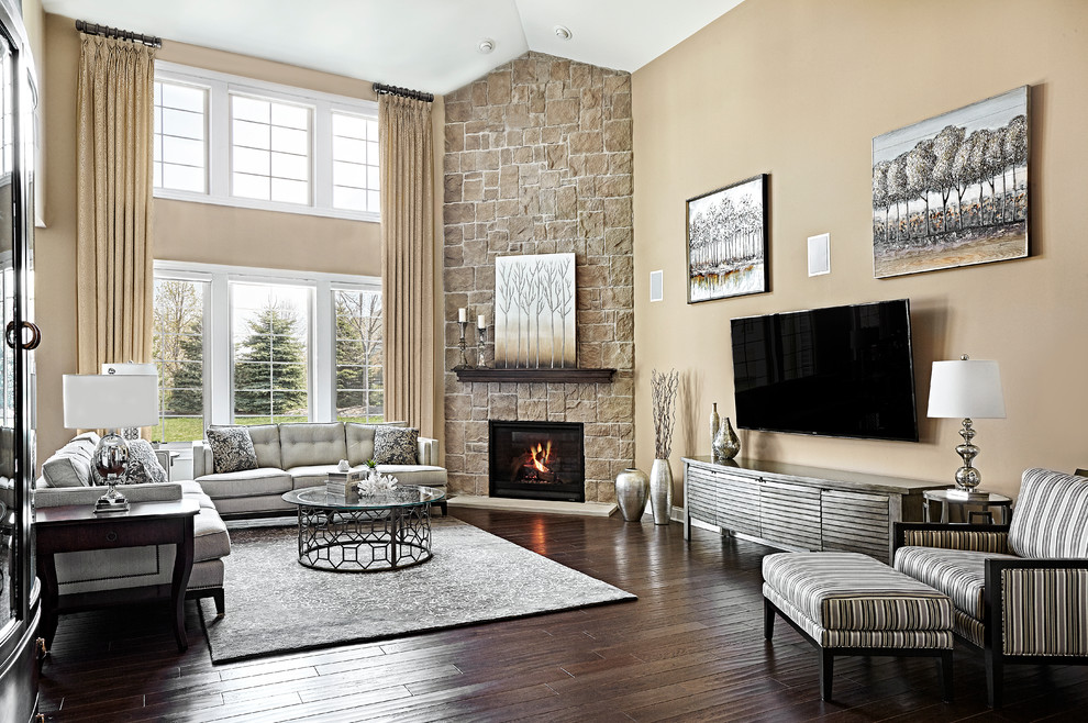 На фото: большая изолированная гостиная комната в современном стиле с коричневыми стенами, темным паркетным полом, угловым камином, фасадом камина из камня, телевизором на стене и ковром на полу с