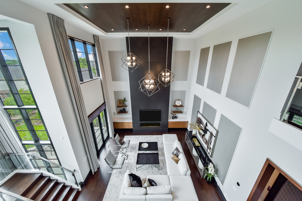 На фото: большая открытая гостиная комната в стиле модернизм с белыми стенами, темным паркетным полом, горизонтальным камином, фасадом камина из плитки, телевизором на стене, синим полом и деревянным потолком с