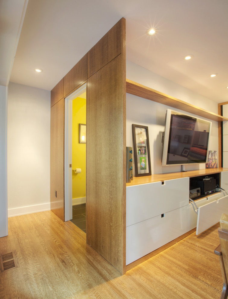 Foto på ett mellanstort minimalistiskt allrum med öppen planlösning, med vita väggar, ljust trägolv och en väggmonterad TV