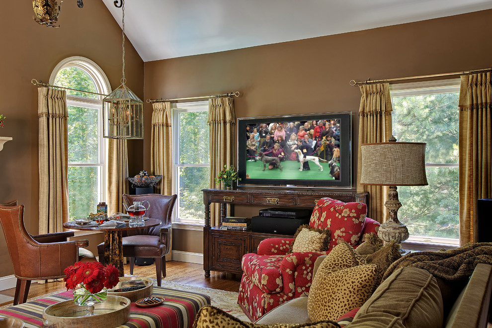 Diseño de sala de estar cerrada tradicional de tamaño medio con paredes marrones, suelo de madera en tonos medios, televisor colgado en la pared y suelo marrón