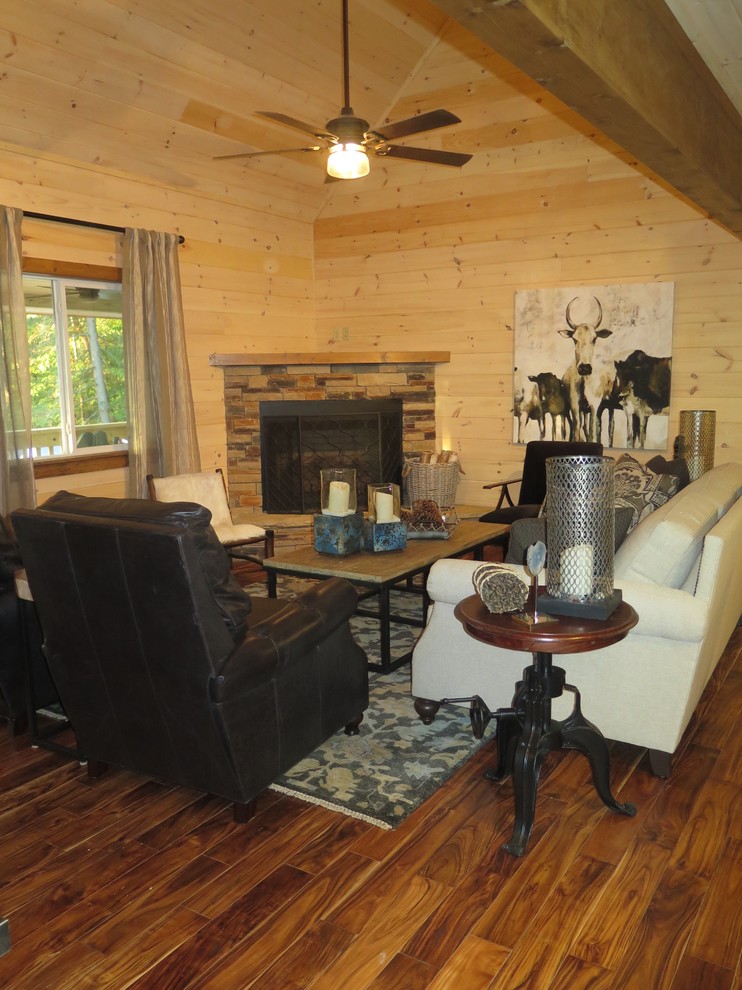Inspiration pour une petite salle de séjour chalet ouverte avec un sol en bois brun, une cheminée d'angle et un manteau de cheminée en pierre.