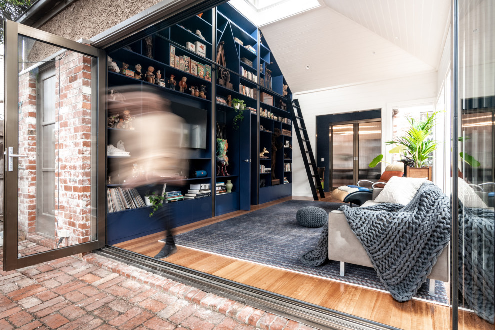 Mittelgroße, Abgetrennte Moderne Bibliothek ohne Kamin mit weißer Wandfarbe, braunem Holzboden, Multimediawand und braunem Boden in Hobart