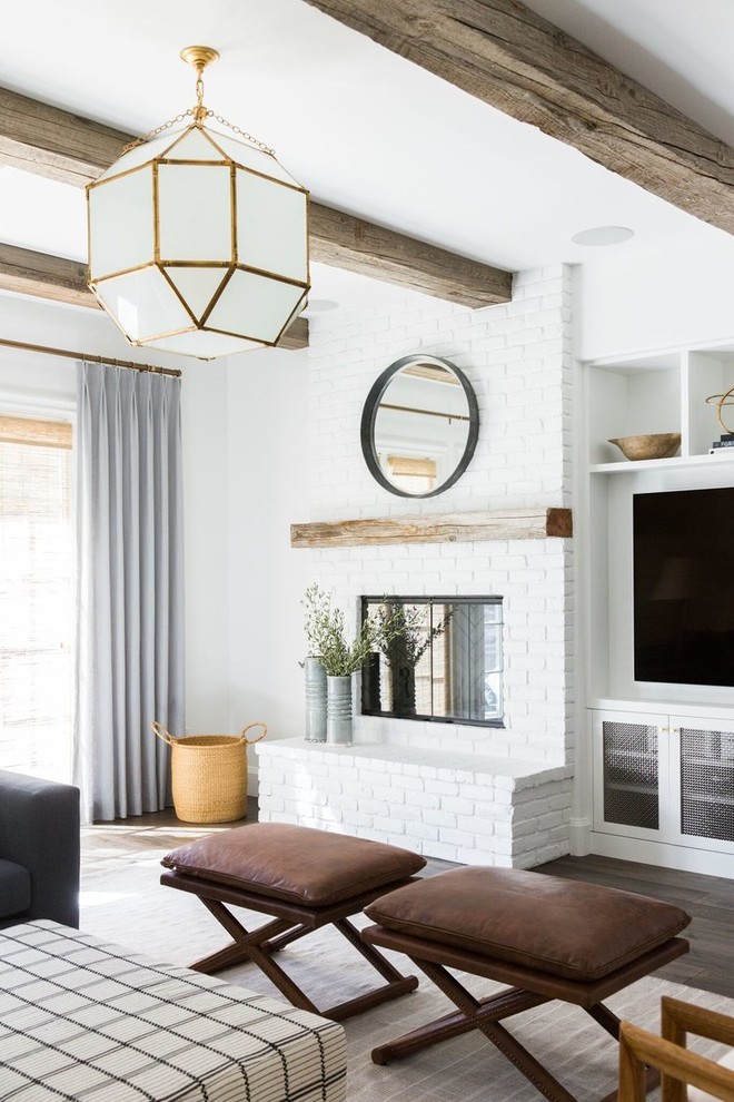 Modelo de sala de estar abierta clásica renovada de tamaño medio con paredes blancas, suelo de madera oscura, todas las chimeneas, marco de chimenea de ladrillo y pared multimedia