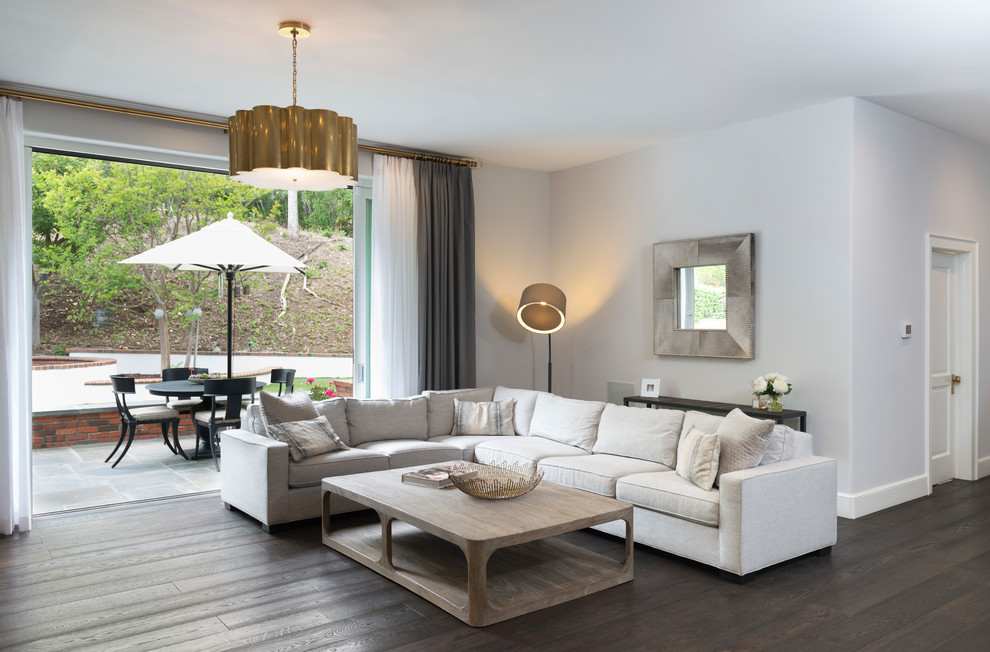 Modelo de sala de estar abierta clásica renovada de tamaño medio sin chimenea y televisor con paredes grises, suelo de madera oscura y suelo marrón