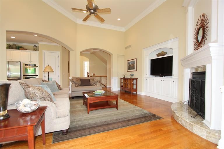 Mittelgroßes, Offenes Klassisches Wohnzimmer mit beiger Wandfarbe, braunem Holzboden, Eckkamin, Kaminumrandung aus Stein und TV-Wand in Cincinnati
