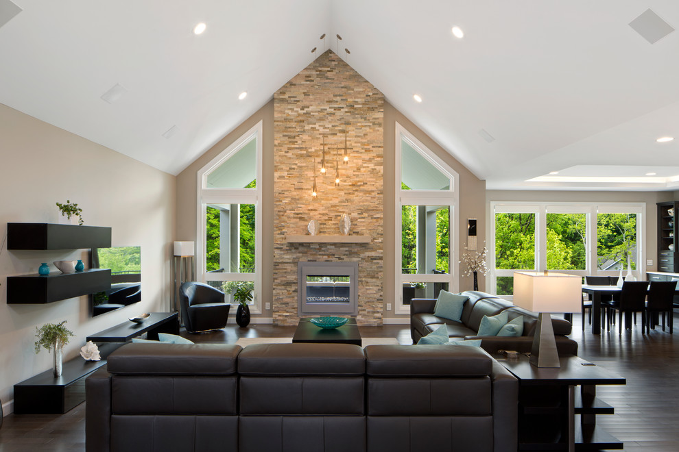 Foto de sala de estar moderna grande con paredes grises, chimenea de doble cara y marco de chimenea de piedra