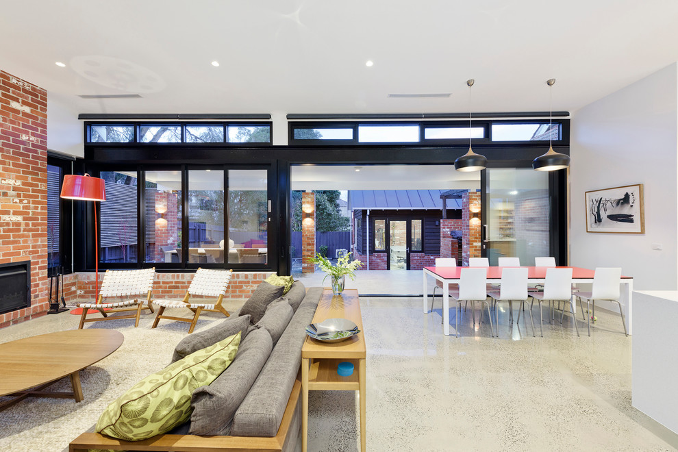Example of a large trendy open concept concrete floor family room design in Melbourne with white walls, a standard fireplace, a brick fireplace and a wall-mounted tv