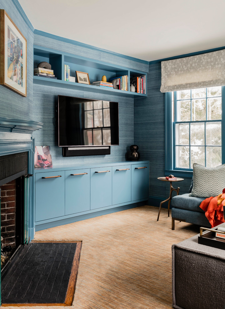 На фото: изолированная гостиная комната среднего размера в стиле неоклассика (современная классика) с с книжными шкафами и полками, синими стенами, ковровым покрытием, стандартным камином, фасадом камина из дерева, мультимедийным центром и оранжевым полом с