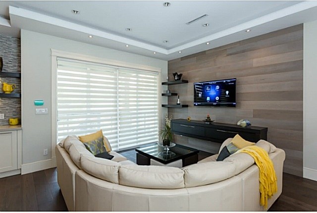 Imagen de sala de estar abierta actual pequeña sin chimenea con paredes grises, suelo de madera oscura, televisor colgado en la pared y suelo marrón