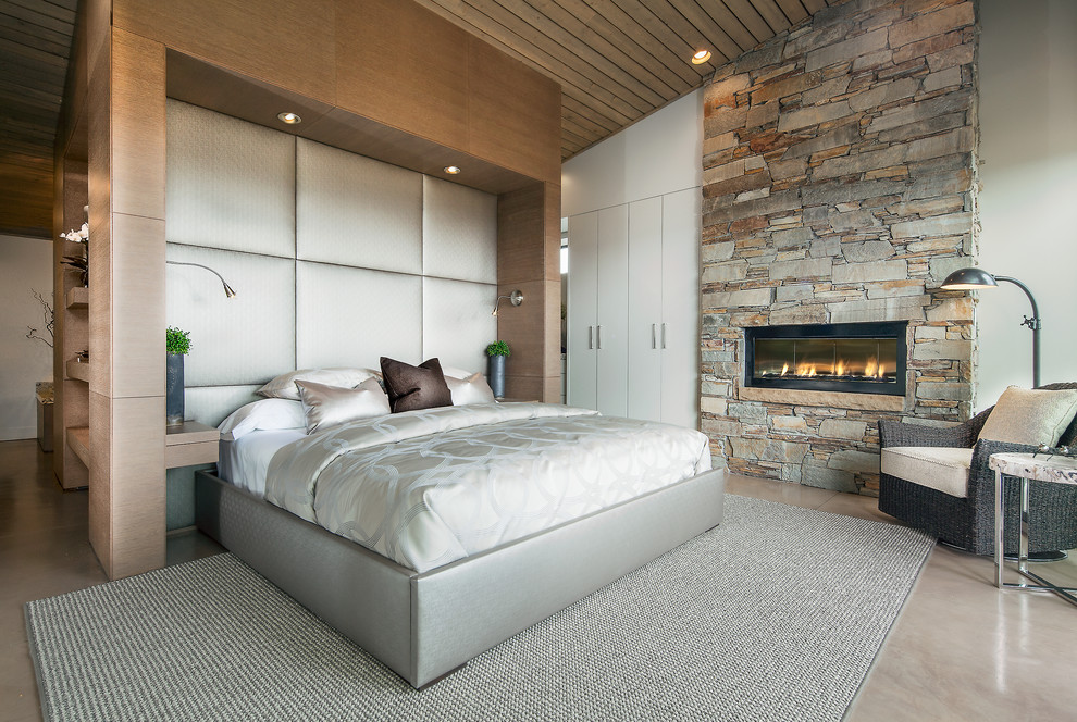 Immagine di una piccola camera da letto contemporanea con pareti bianche, pavimento in cemento e camino classico