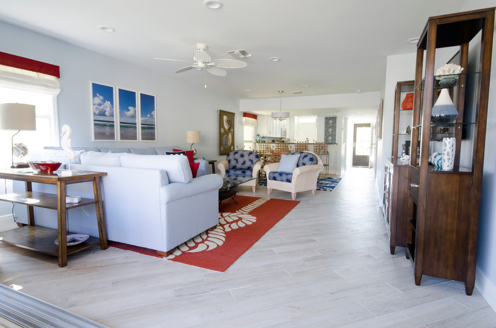 マイアミにある高級な広いビーチスタイルのおしゃれなオープンリビング (青い壁、セラミックタイルの床、据え置き型テレビ) の写真