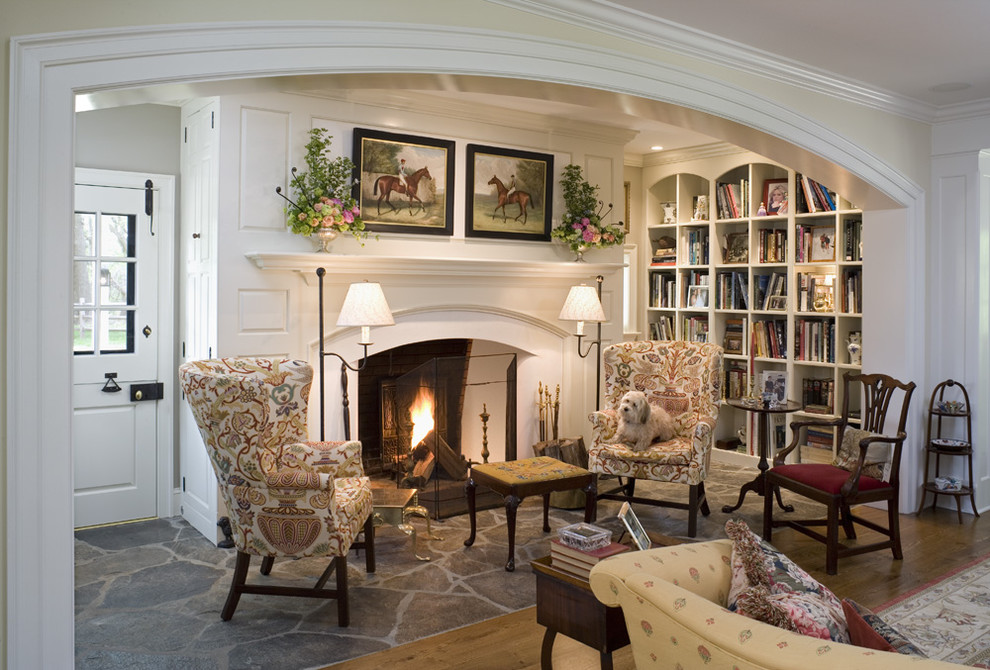 Пример оригинального дизайна: гостиная комната в классическом стиле с с книжными шкафами и полками, бежевыми стенами, стандартным камином, фасадом камина из дерева и полом из сланца без телевизора