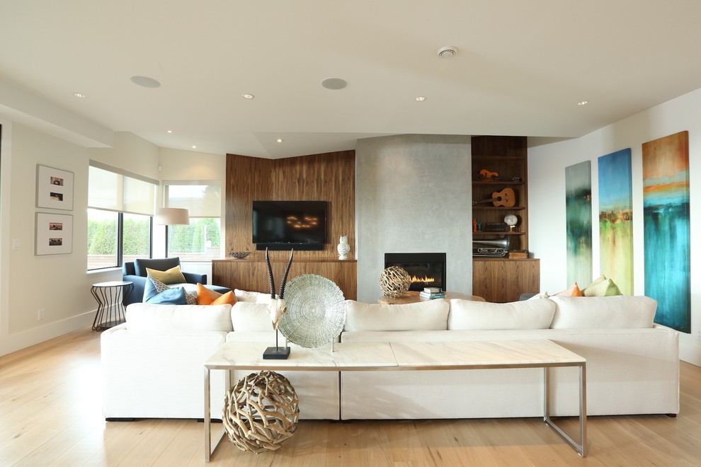 Ejemplo de sala de estar abierta contemporánea grande con paredes blancas, suelo de madera clara, todas las chimeneas, marco de chimenea de hormigón y televisor colgado en la pared