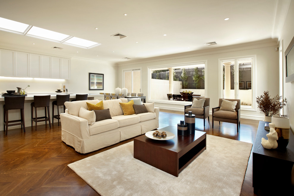 Aménagement d'une grande salle de séjour classique ouverte avec un mur blanc, un sol en bois brun et aucune cheminée.