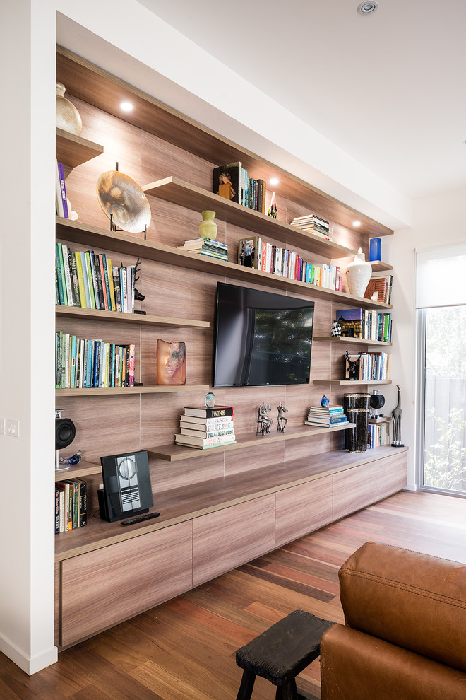 Diseño de sala de estar abierta actual de tamaño medio con paredes blancas, suelo de madera en tonos medios y televisor colgado en la pared