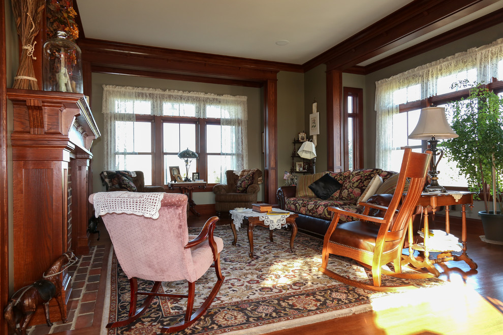Cette image montre une salle de séjour craftsman de taille moyenne et fermée avec un mur beige, un sol en bois brun, une cheminée standard, un manteau de cheminée en pierre, aucun téléviseur et un sol marron.