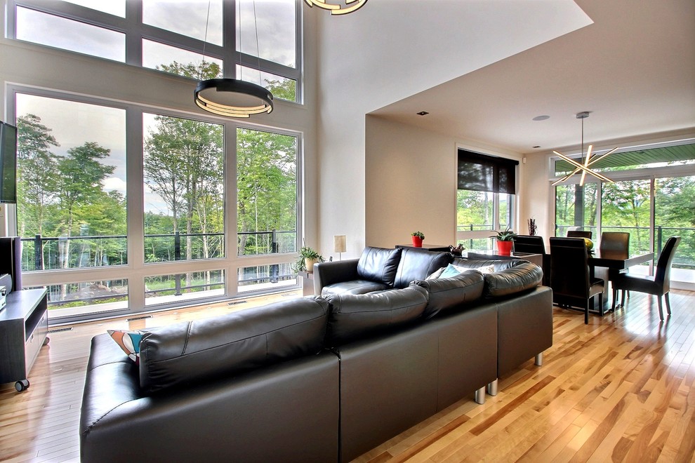 Mittelgroßes, Offenes Modernes Wohnzimmer mit weißer Wandfarbe, TV-Wand und hellem Holzboden in Montreal