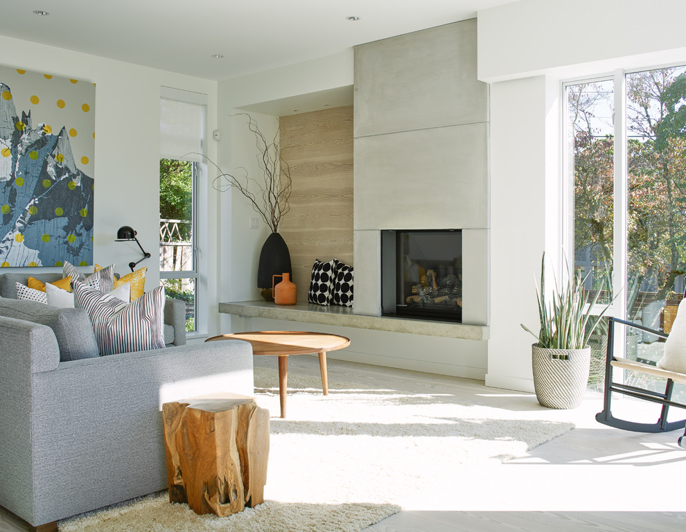 Imagen de sala de estar abierta actual de tamaño medio con paredes blancas, suelo de madera clara, todas las chimeneas y marco de chimenea de hormigón