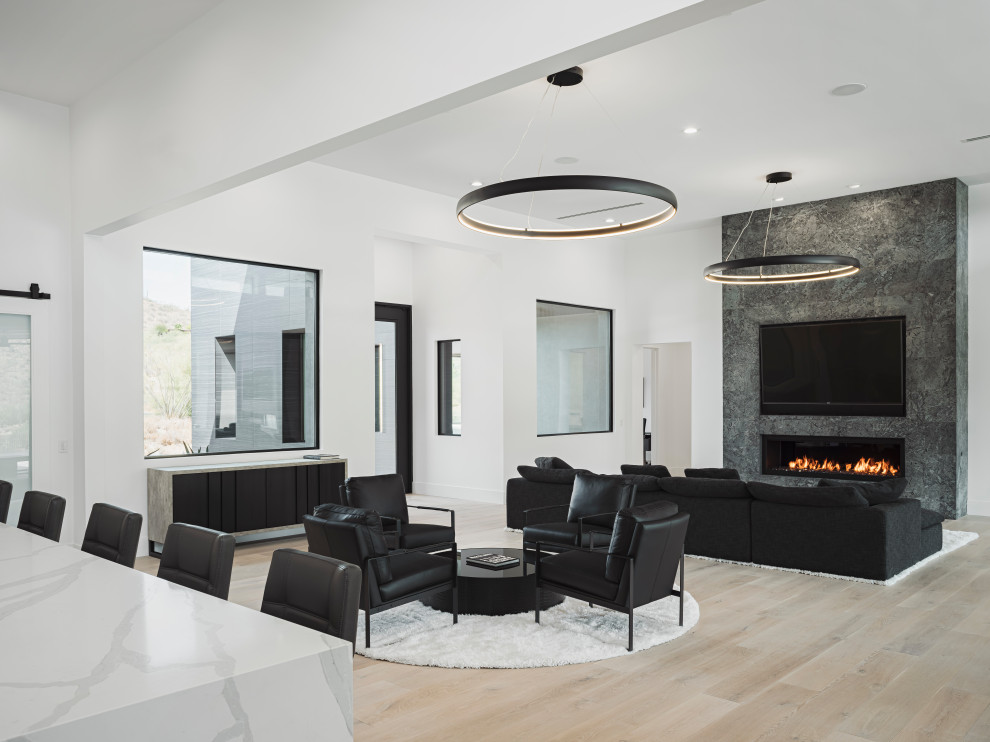 Design ideas for a large modern open plan games room in Phoenix with a game room, white walls, light hardwood flooring, a standard fireplace, a tiled fireplace surround, a wall mounted tv and beige floors.