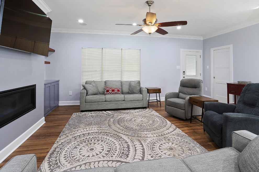Cette image montre une salle de séjour traditionnelle de taille moyenne et ouverte avec un sol en vinyl, un téléviseur fixé au mur, un sol marron, un mur gris, une cheminée ribbon et un manteau de cheminée en plâtre.
