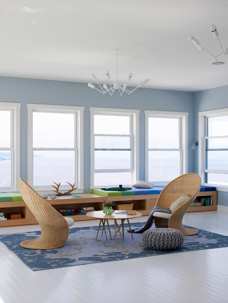 Cette photo montre une salle de séjour bord de mer ouverte avec un mur bleu, parquet peint, aucune cheminée et un sol blanc.