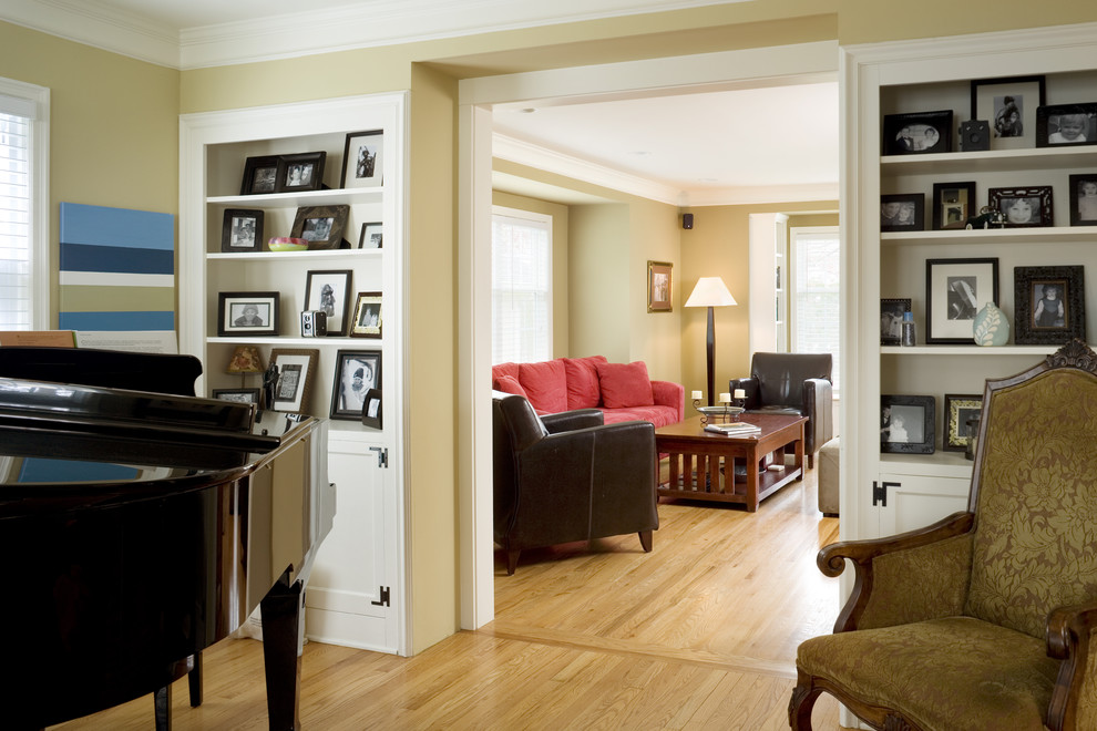 Foto de sala de estar con rincón musical abierta clásica pequeña con paredes amarillas, suelo de madera en tonos medios y televisor retractable