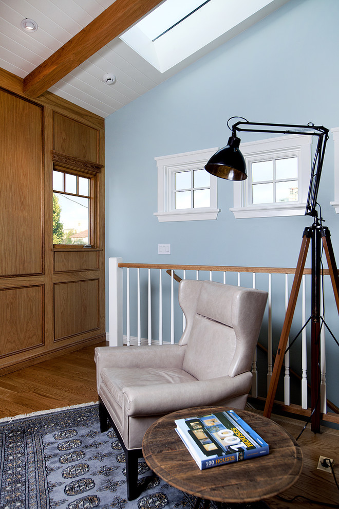 Idée de décoration pour une petite salle de séjour mansardée ou avec mezzanine design avec un mur bleu, un sol en bois brun, aucune cheminée, un téléviseur fixé au mur et un sol marron.