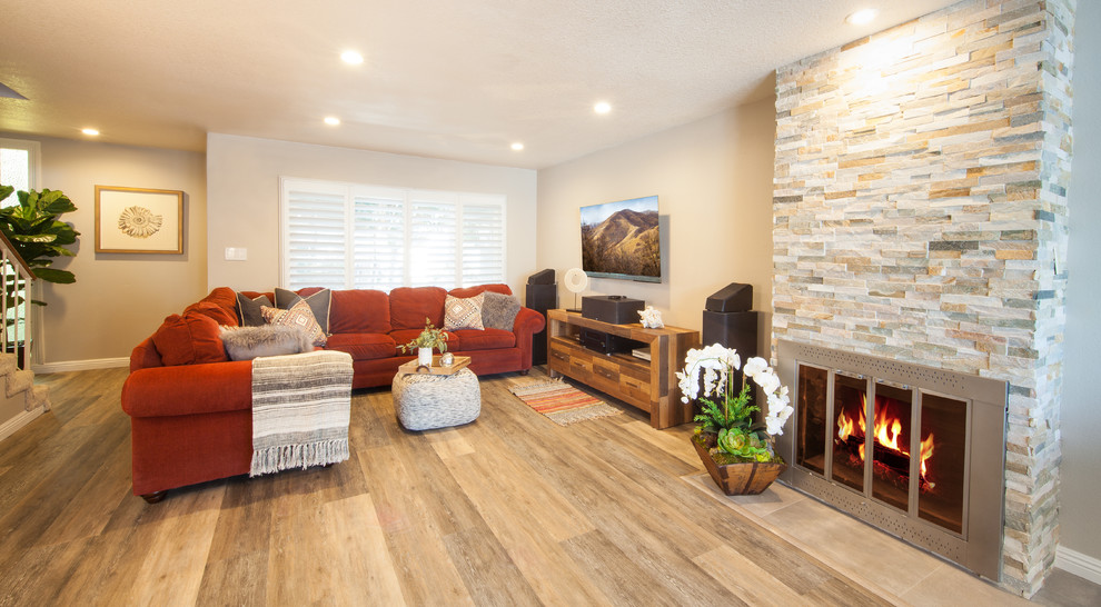 Photo of a small rustic enclosed games room in Orange County with grey walls, vinyl flooring, a standard fireplace, a tiled fireplace surround, a wall mounted tv and grey floors.