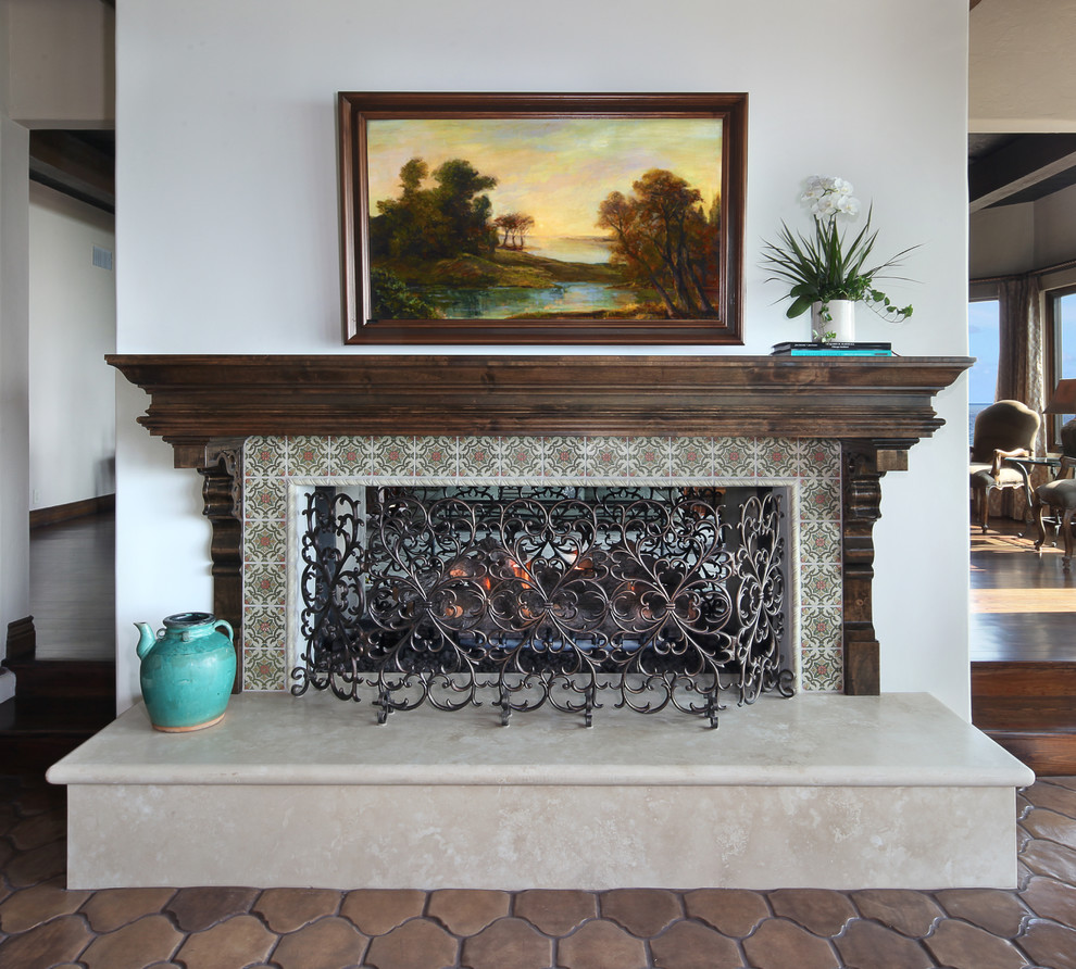 This is an example of a mediterranean games room in Orange County with terracotta flooring, a two-sided fireplace and a tiled fireplace surround.