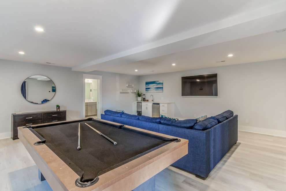 Diseño de sala de juegos en casa costera extra grande con suelo vinílico, televisor colgado en la pared y suelo gris