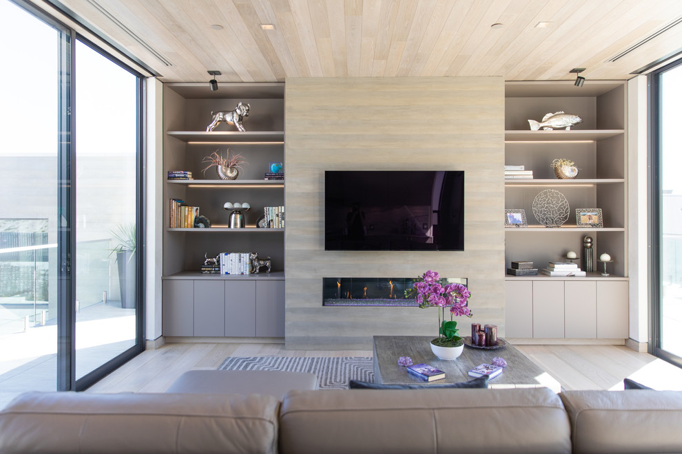Example of a trendy light wood floor and beige floor family room design in Los Angeles with beige walls, a ribbon fireplace and a wall-mounted tv