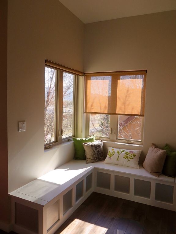 Cette image montre une petite salle de séjour mansardée ou avec mezzanine urbaine avec un mur beige et un sol en bois brun.