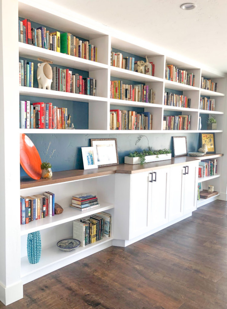 Cette photo montre une salle de séjour rétro avec une bibliothèque ou un coin lecture, un mur bleu, parquet foncé et un sol marron.