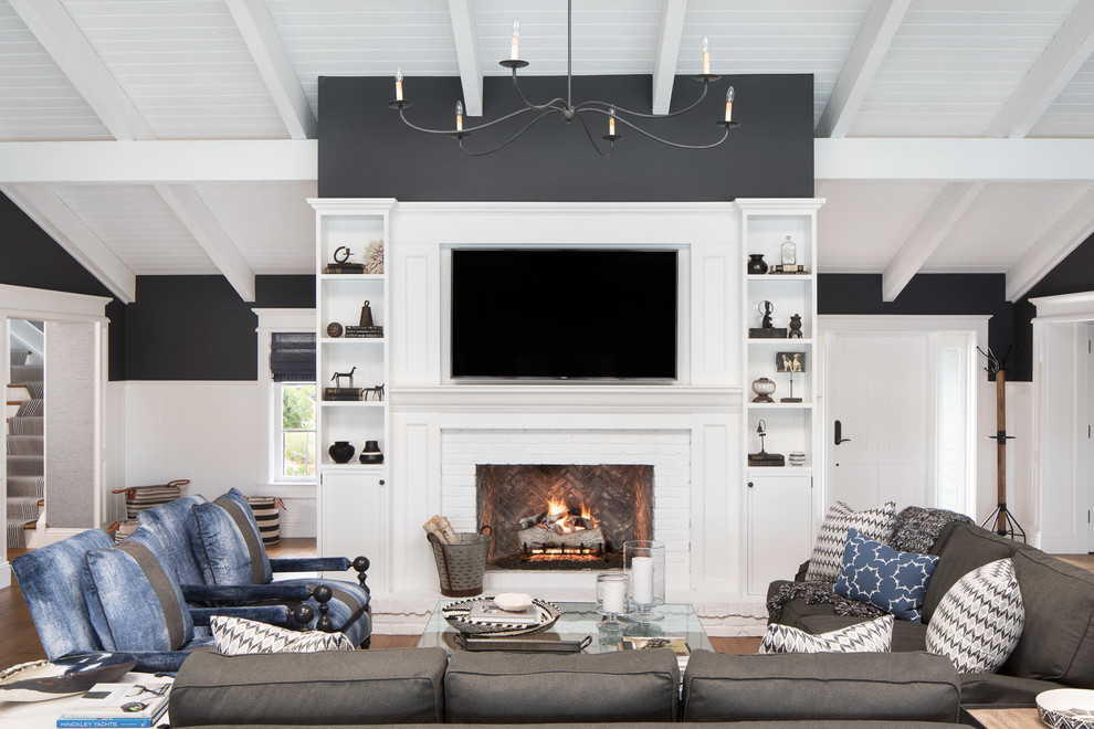 Large beach style open concept medium tone wood floor and brown floor family room photo in Miami with black walls, a standard fireplace, a brick fireplace and a wall-mounted tv