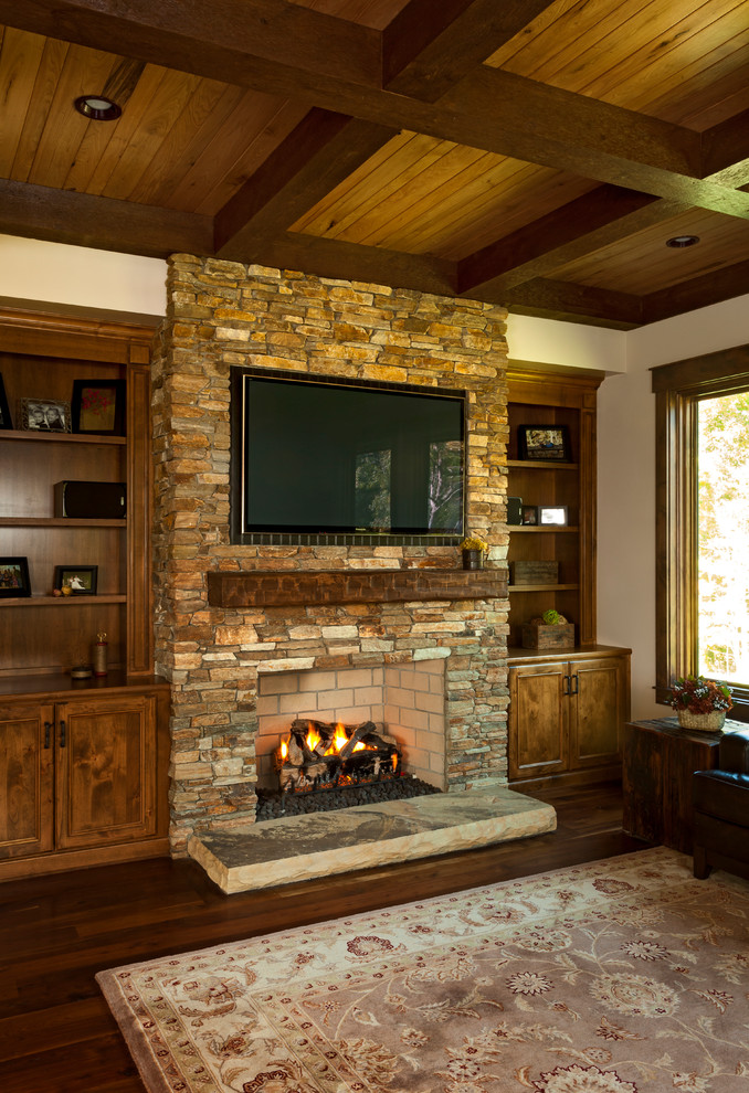 Inspiration for a mid-sized rustic enclosed dark wood floor and brown floor family room remodel in Charlotte with beige walls, a standard fireplace, a stone fireplace and a wall-mounted tv
