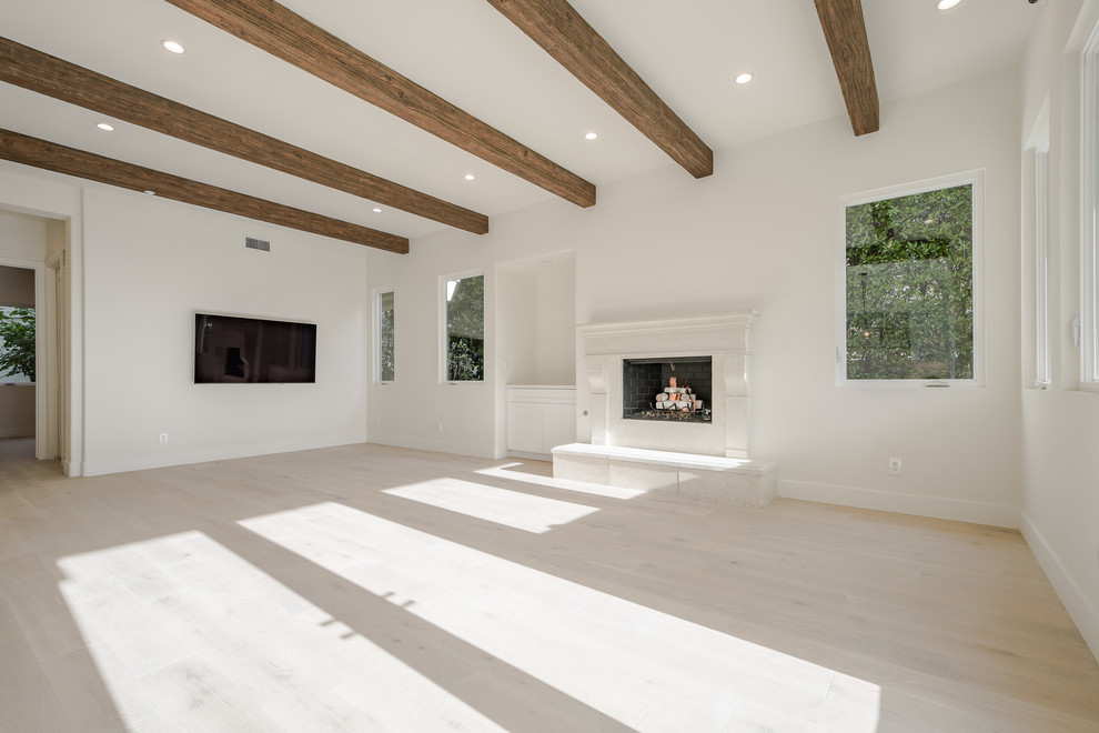 Großes, Offenes Skandinavisches Wohnzimmer mit weißer Wandfarbe, hellem Holzboden, Kamin, verputzter Kaminumrandung, TV-Wand und beigem Boden in Los Angeles