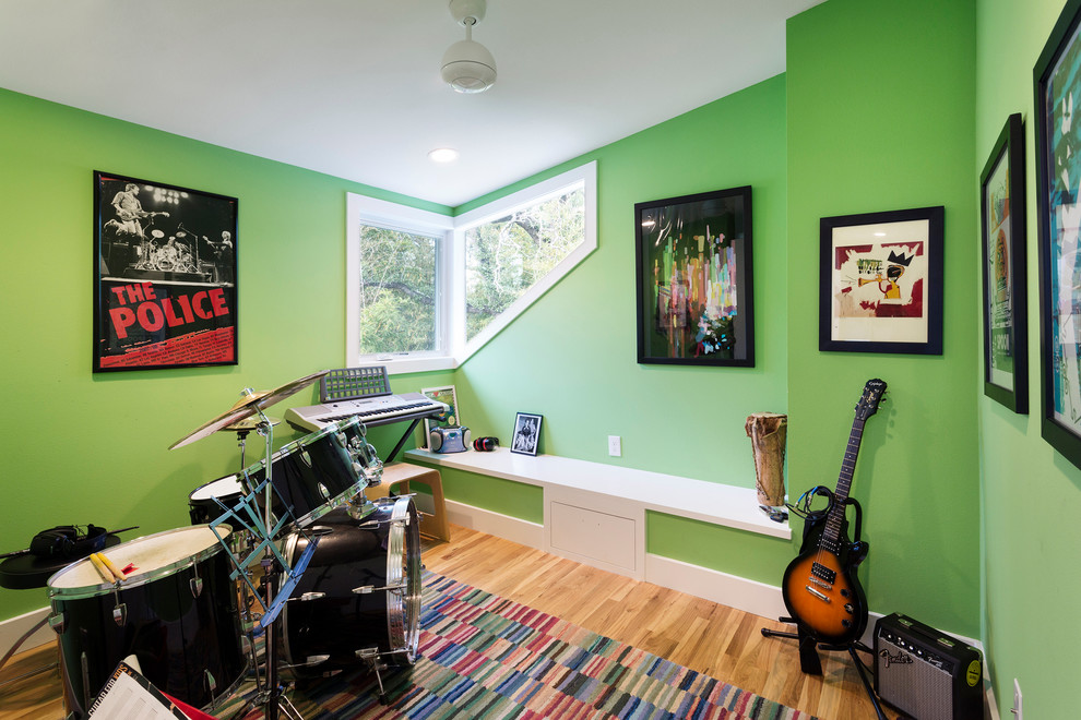 Bild på ett litet funkis allrum, med gröna väggar, ljust trägolv och ett musikrum