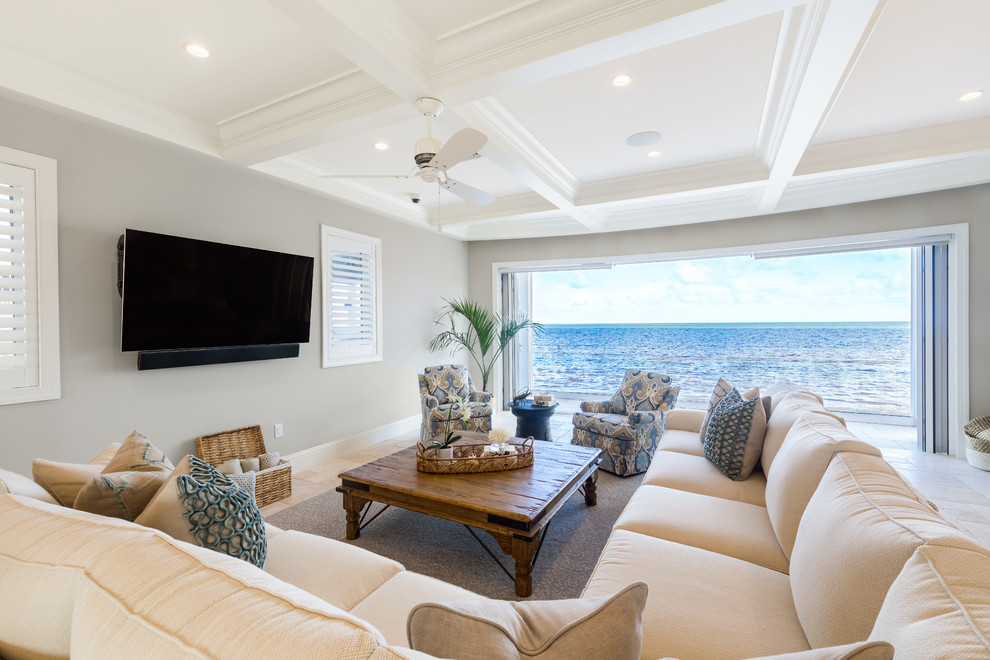 Immagine di un soggiorno stile marino aperto con pareti grigie, nessun camino, TV a parete e pavimento beige