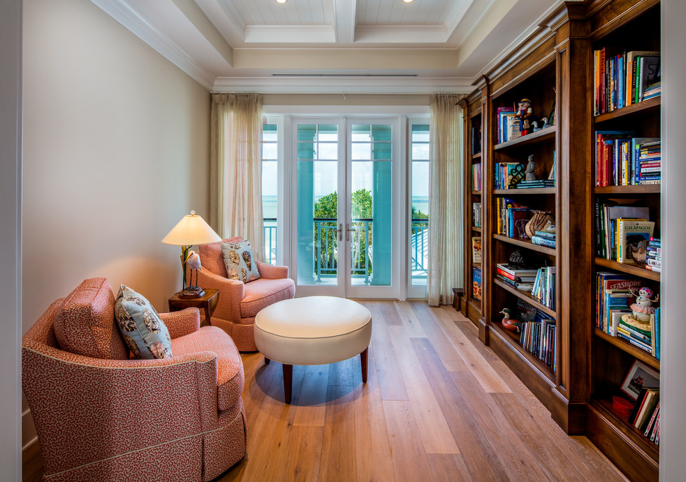 Ispirazione per un soggiorno stile marino chiuso con libreria, pareti beige, pavimento in legno massello medio e pavimento marrone