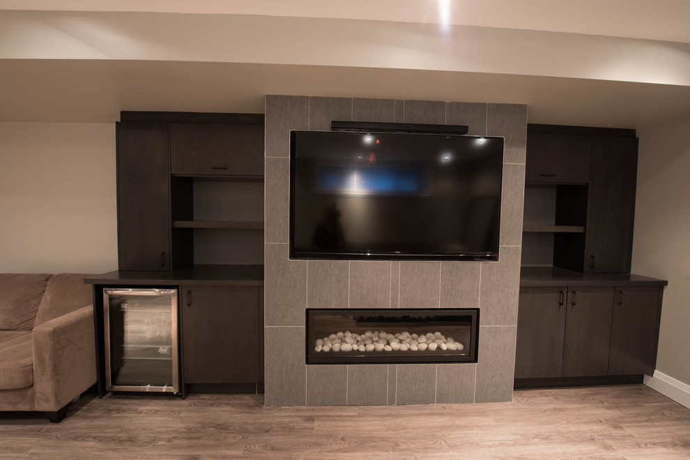 This is an example of a medium sized contemporary games room in Toronto with grey walls, medium hardwood flooring, a ribbon fireplace, a tiled fireplace surround and a built-in media unit.