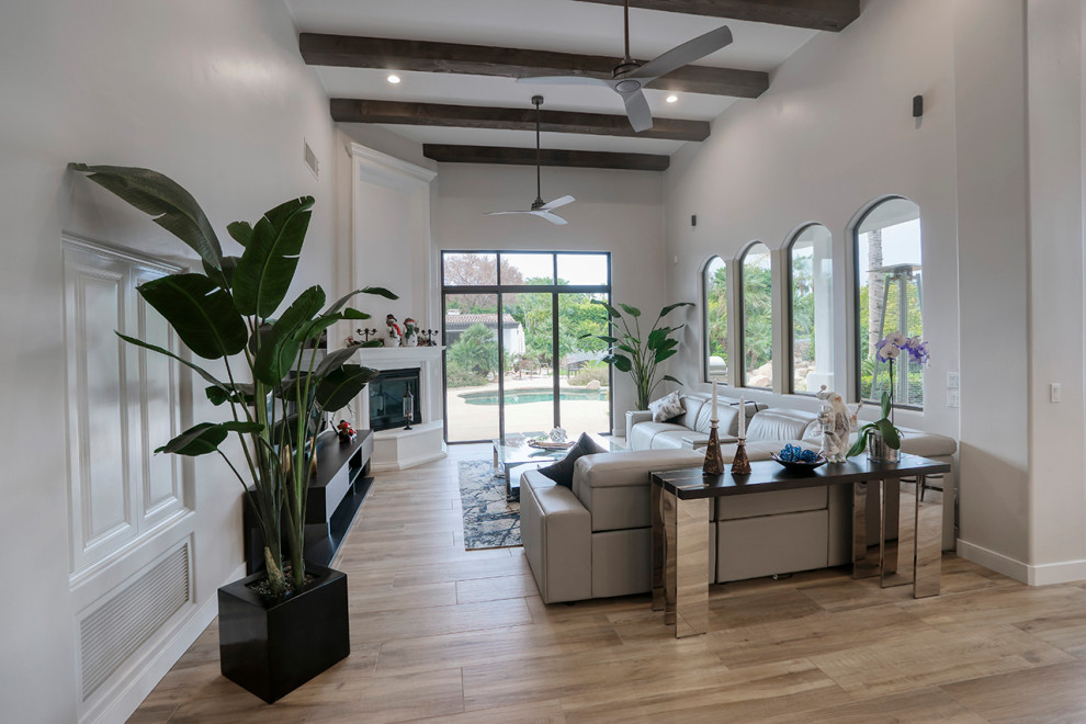 Geräumiges, Abgetrenntes Modernes Wohnzimmer mit grauer Wandfarbe, hellem Holzboden, Eckkamin, verputzter Kaminumrandung, TV-Wand und braunem Boden in Phoenix
