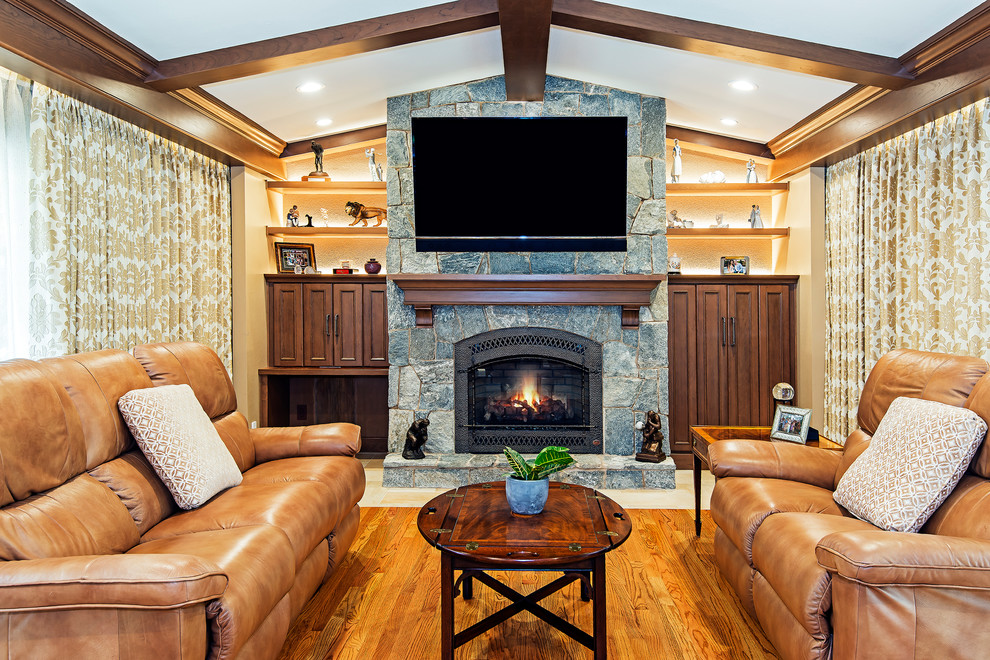 Mid-sized elegant open concept medium tone wood floor and brown floor family room photo in Other with brown walls, a standard fireplace, a stone fireplace and a wall-mounted tv