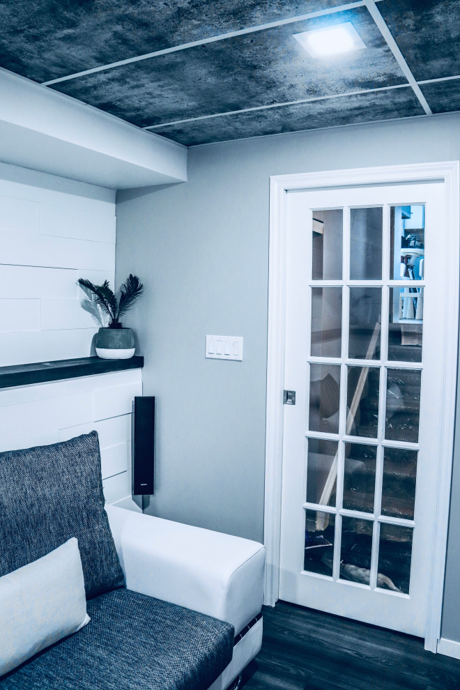 Cette photo montre une salle de séjour moderne de taille moyenne et fermée avec une salle de musique, un mur blanc, un sol en vinyl, un téléviseur fixé au mur et un sol gris.