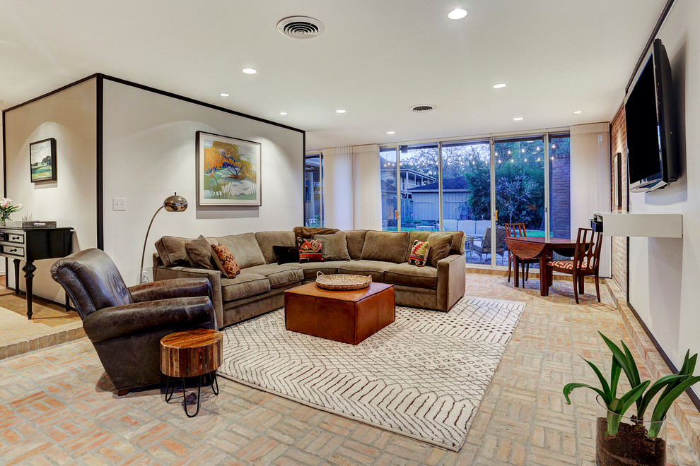 Photo of a large midcentury open plan games room in Houston with a game room, white walls, brick flooring, no fireplace and a wall mounted tv.