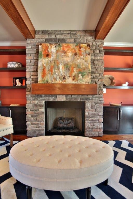 Idée de décoration pour une grande salle de séjour tradition ouverte avec un mur orange, une cheminée standard, un manteau de cheminée en pierre et un téléviseur fixé au mur.