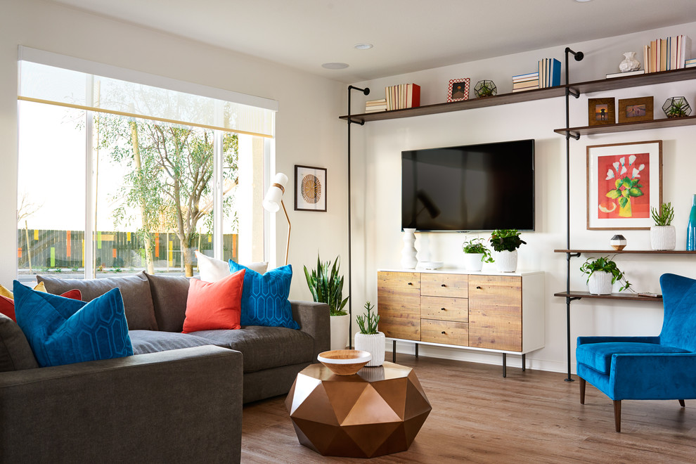 Modelo de sala de estar tradicional renovada con paredes blancas, suelo de madera en tonos medios y televisor colgado en la pared