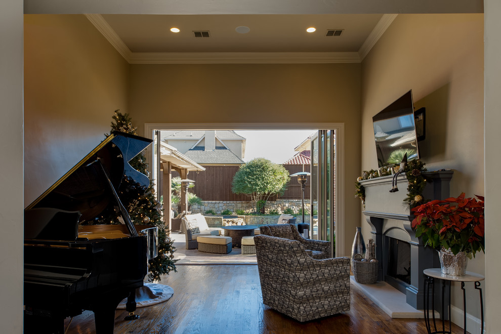 Inspiration for a medium sized classic open plan games room in Dallas with a music area, a standard fireplace, a wooden fireplace surround, a wall mounted tv, brown floors, beige walls and dark hardwood flooring.