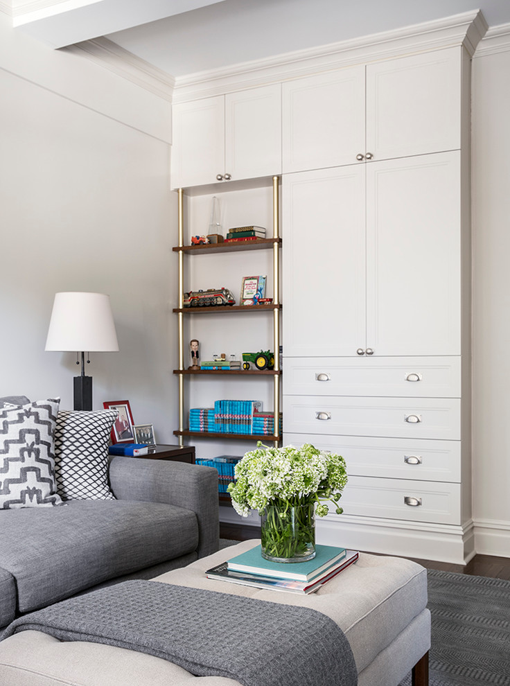 Imagen de sala de estar con biblioteca cerrada clásica pequeña con paredes blancas, suelo de madera en tonos medios y televisor independiente