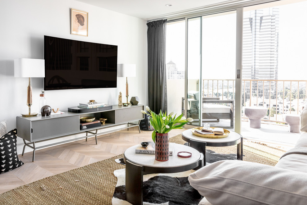 Ejemplo de sala de estar contemporánea con paredes blancas, suelo de madera clara, televisor colgado en la pared y suelo beige