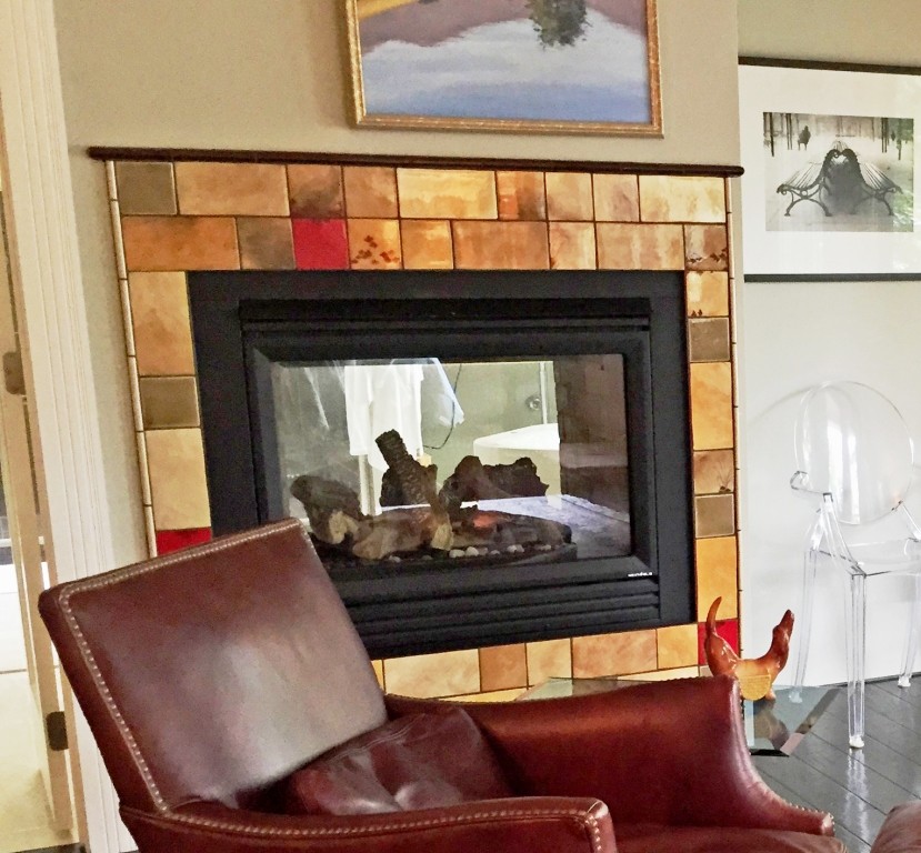 Imagen de sala de estar tradicional de tamaño medio sin televisor con paredes verdes, suelo de madera clara, chimenea de doble cara y marco de chimenea de baldosas y/o azulejos